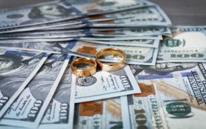 Money with wedding rings on top