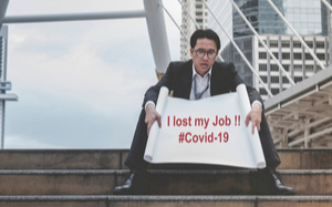 A man with a sign that says "I Lost My Job!! #Covid-19"